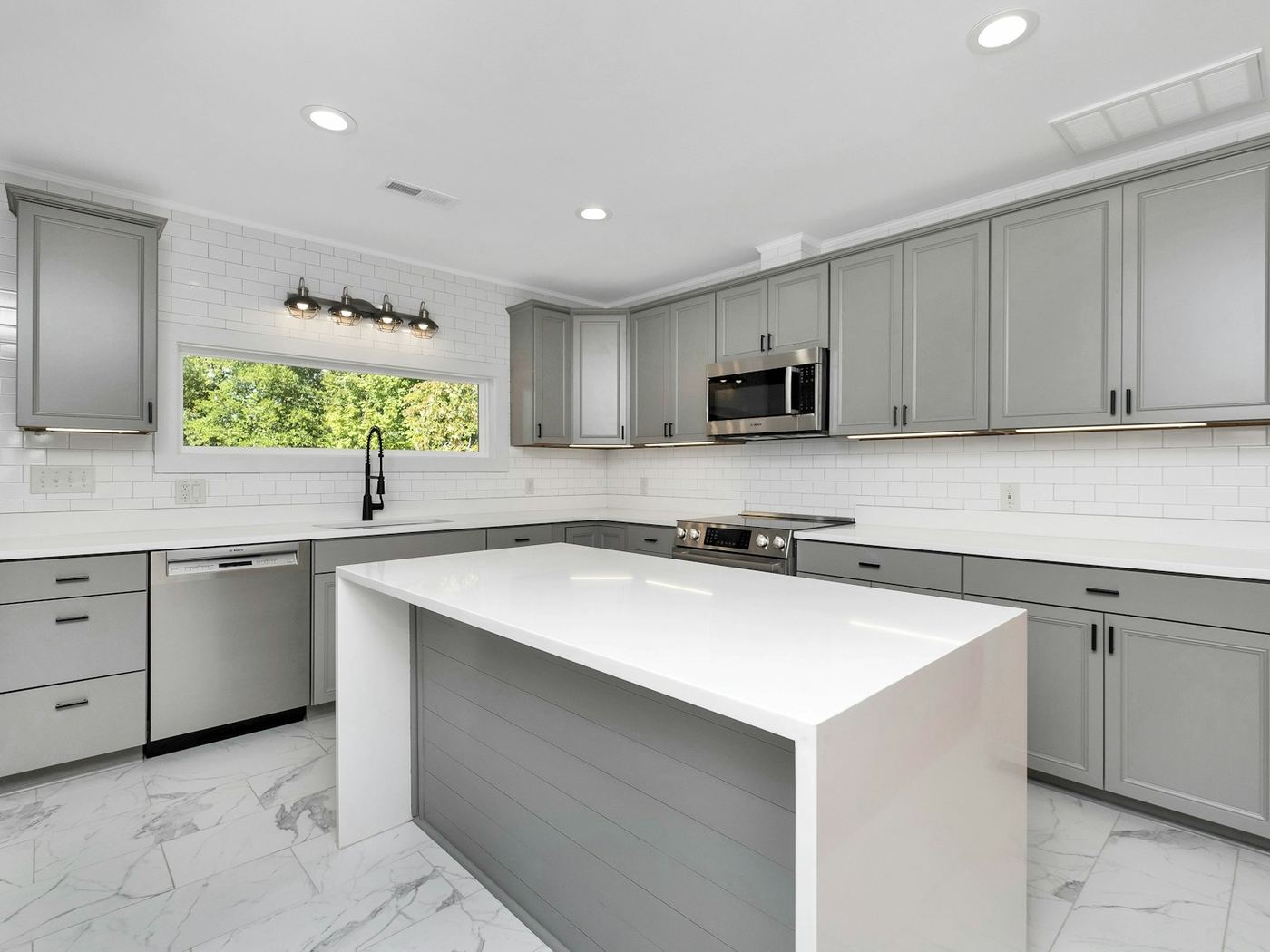 A shaker style kitchen in soft grey with a white island bench.