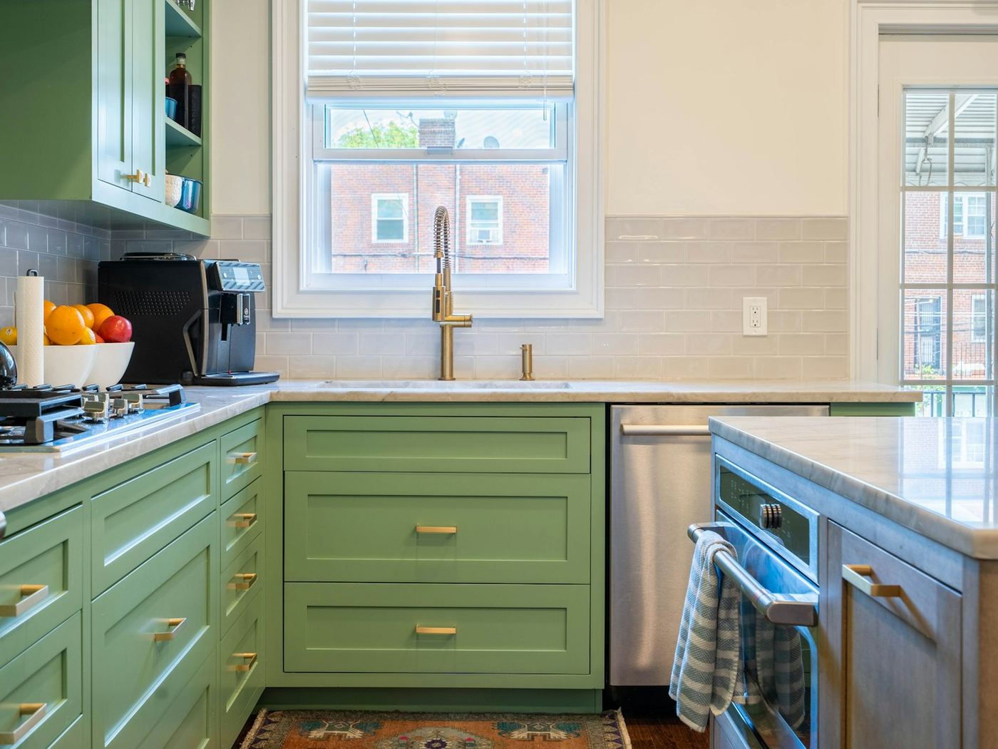 A kitchen with deep green cabinetry and pale benchtops.